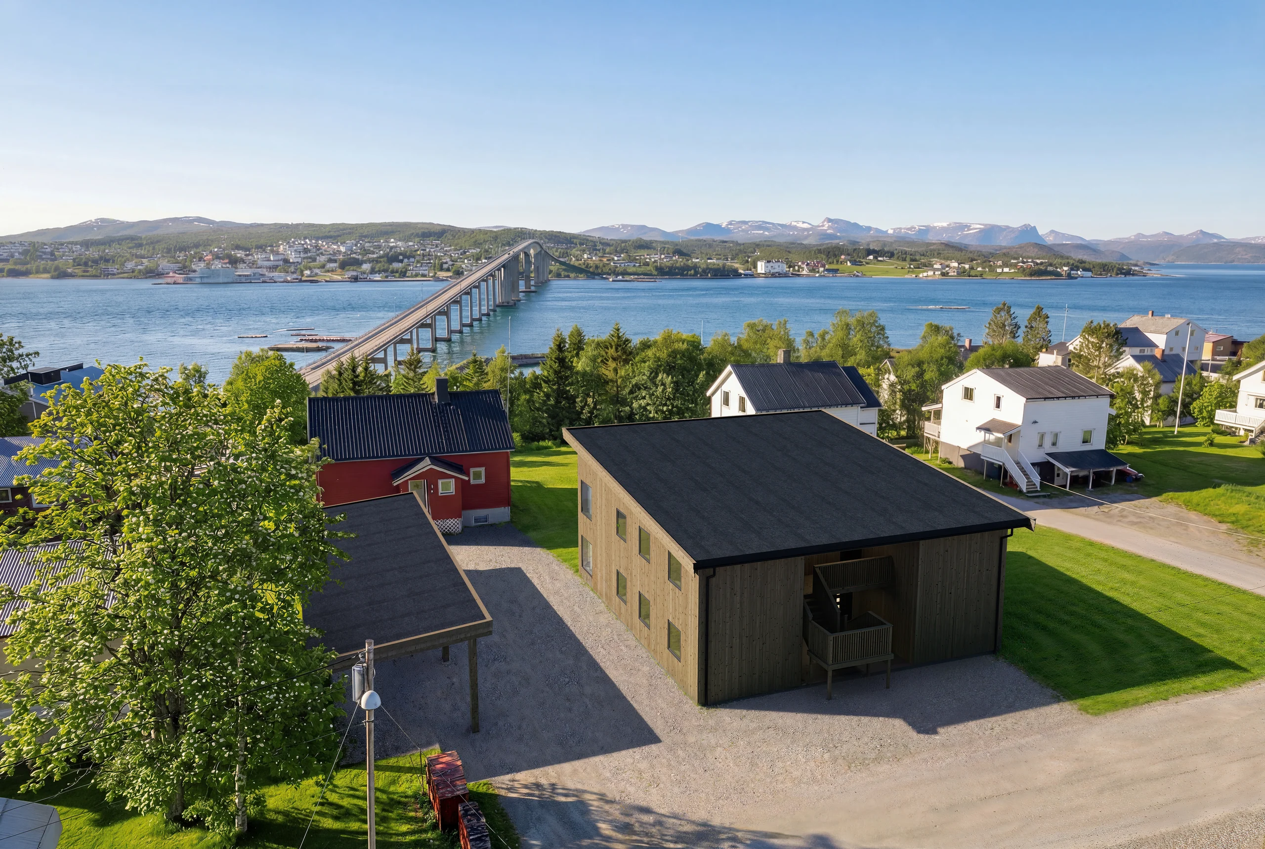 Dronevisualisering av boligprosjektet Nordli i Finnsnes, med Gisundbrua, fjorden og fjellene i bakgrunnen.