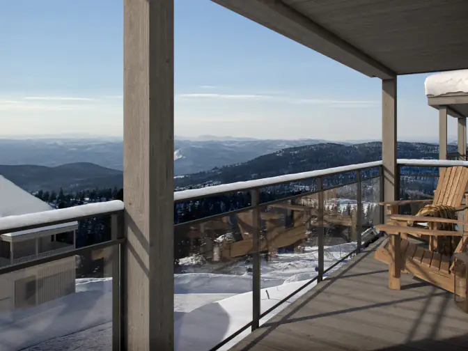 Balkong med glassrekkverk, hyttestol og utsikt over snødekte fjell