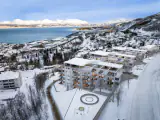 Alpinbyen i Narvik montert i dronefoto med fjorden og vinterlandskapet rundt