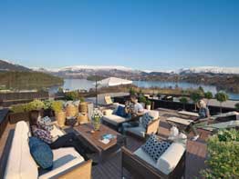 en luftfoto av en terrasse med møbler og utsikt over innsjøen.